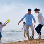 family on beach playing soccer and frisbee